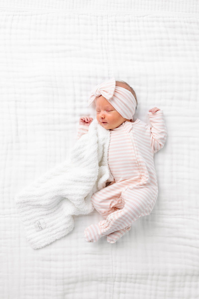 harper zipper footies newborn baby girl laying on bed with white chenille mini