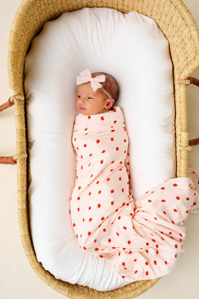 Junie swaddle blanket strawberry print. newborn girl swaddled in bassinet with blush tulle bow