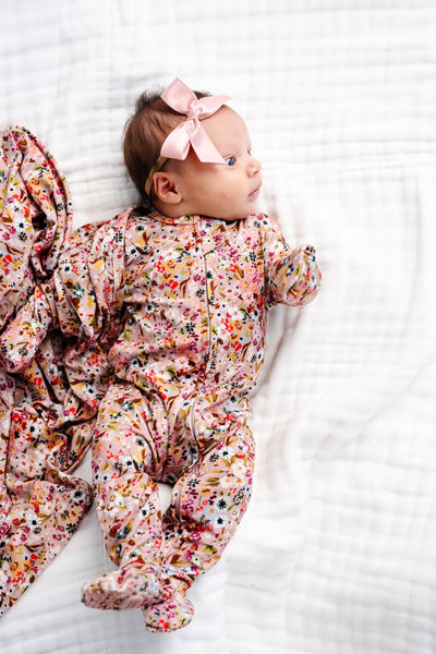 Penelope Zipper Footies newborn girl laying on bed with french pink satin bow