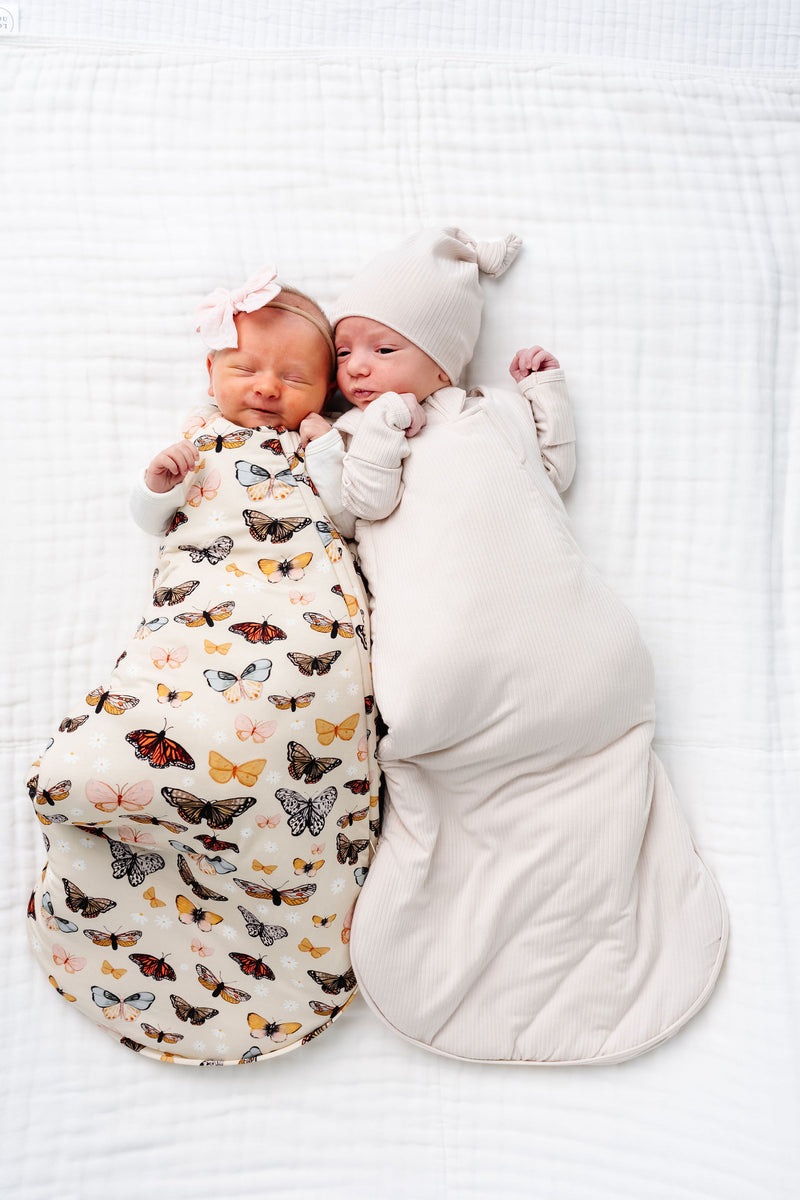 amelia and cove sleep sack newborn girl and boy laying on bed