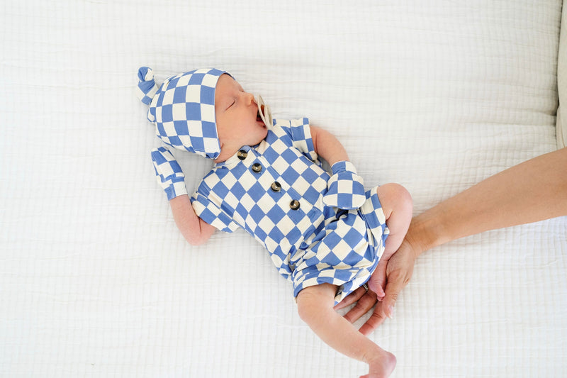 jett romper newborn boy with mittens and top knot hat laying on bed