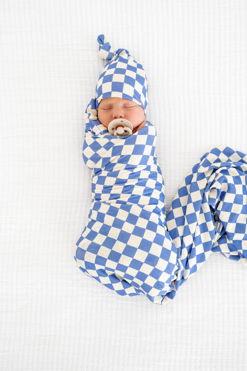 jett swaddle blanket newborn boy swaddled on bed with matching top knot hat