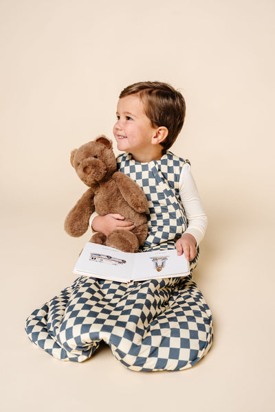 miles sleep sack toddler boy holding bear and book sitting on ground