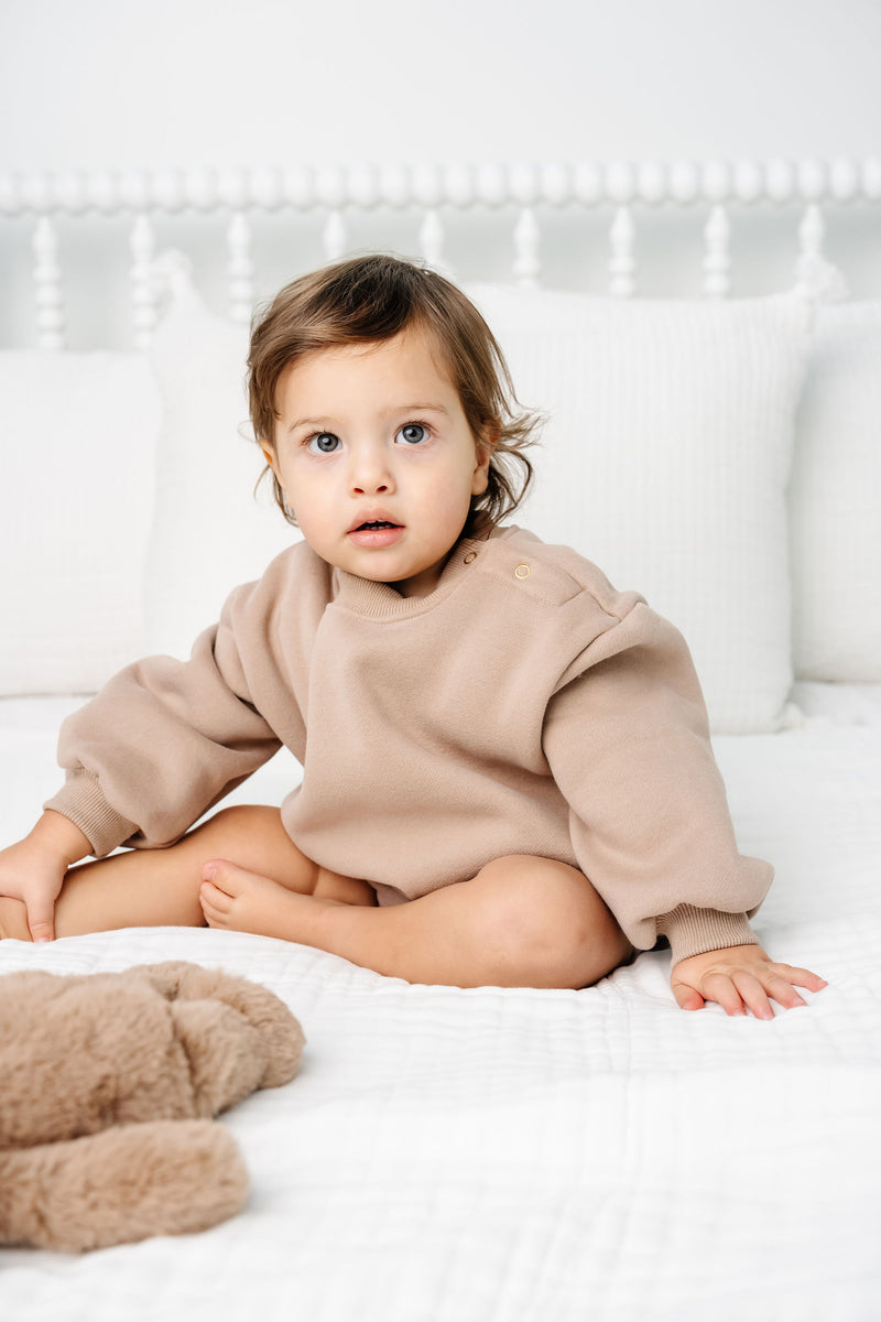 mocha sweatshirt romper toddler boy sitting on bed