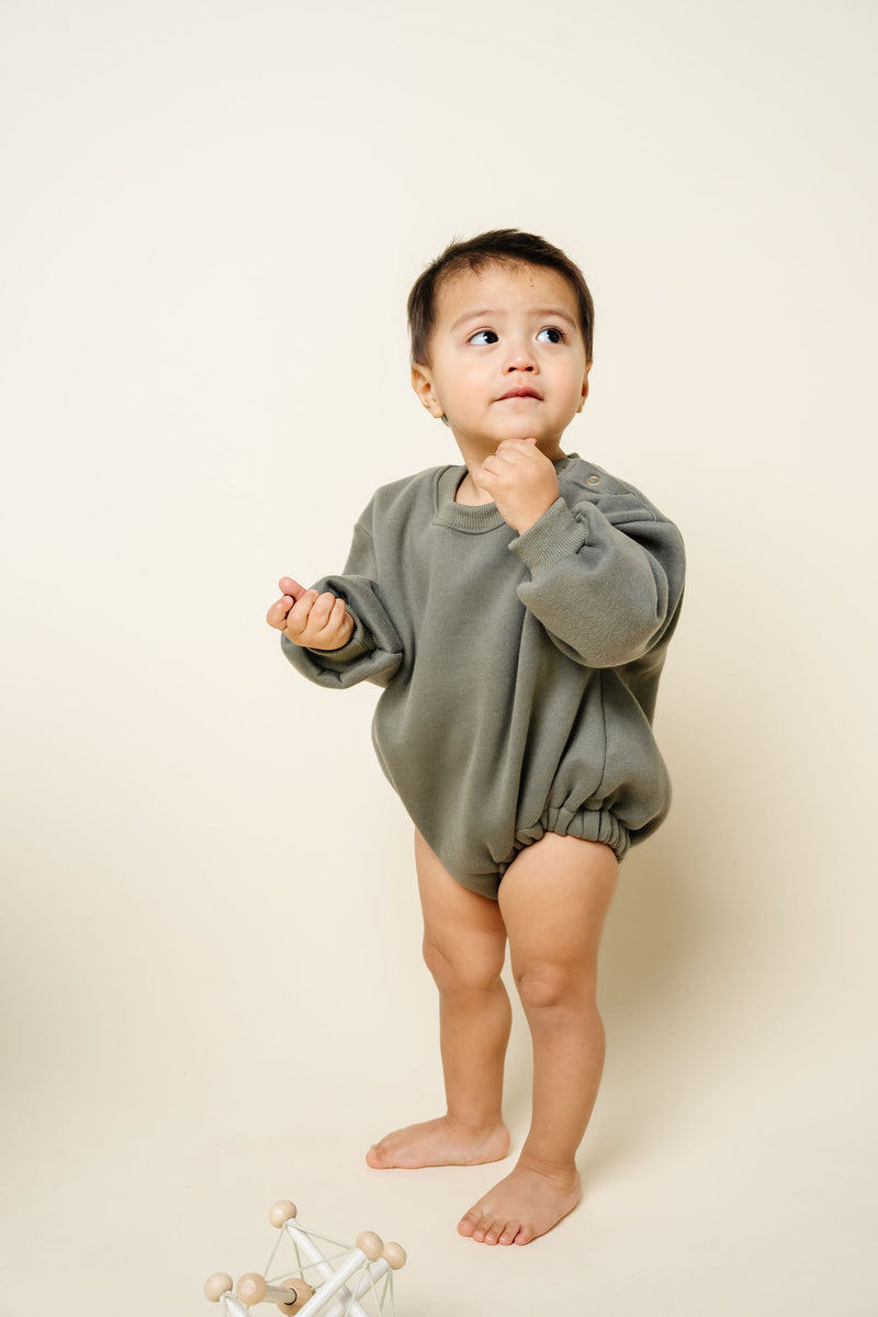 olive sweatshirt romper toddler boy standing with toy