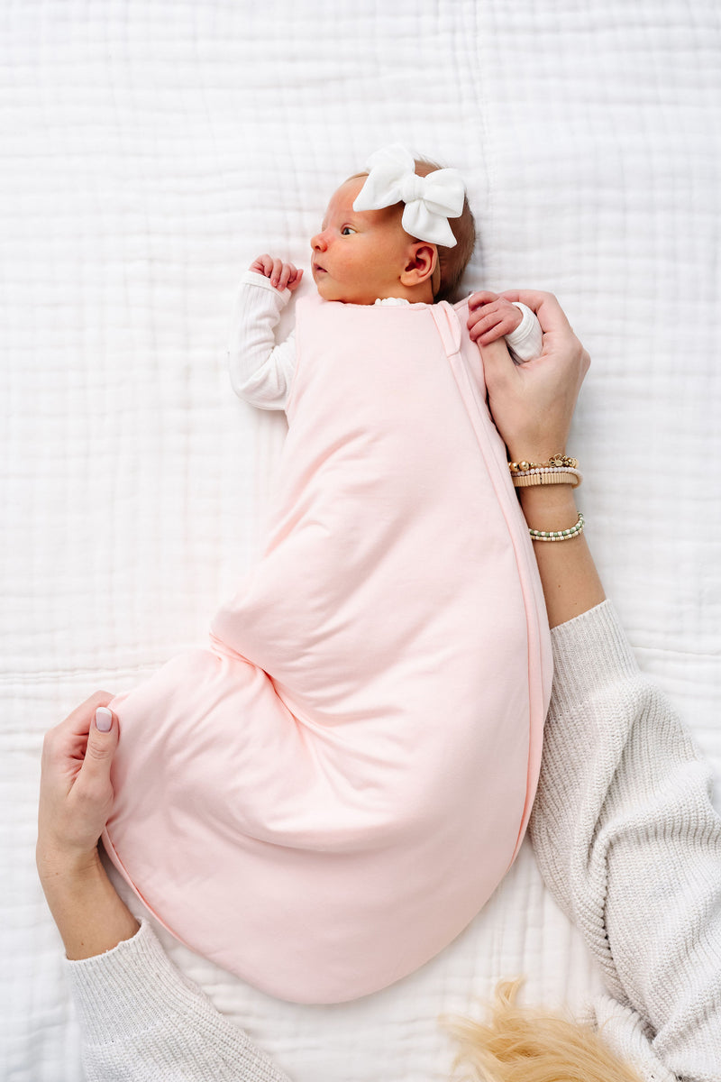 sophie newborn girl wearing a newborn sleep sack laying on bed