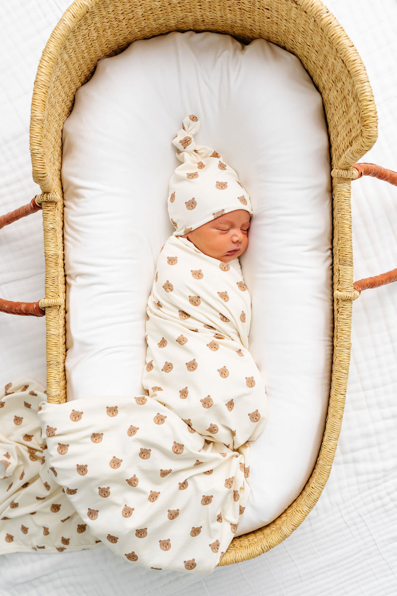 teddy swaddle newborn boy laying in bassinet bear print